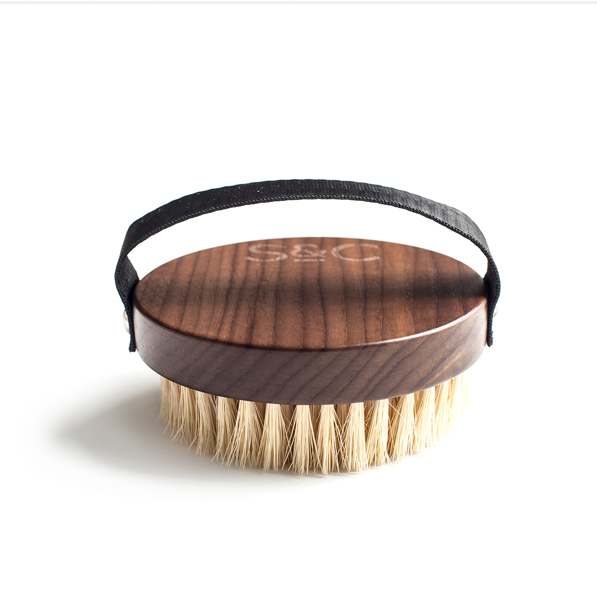 Luxurious Walnut Wood Dry Body Brush by Stass & Co: Round brush with black strap, natural sisal bristles, and handle. Close-up view showcasing bristles and logo detail.